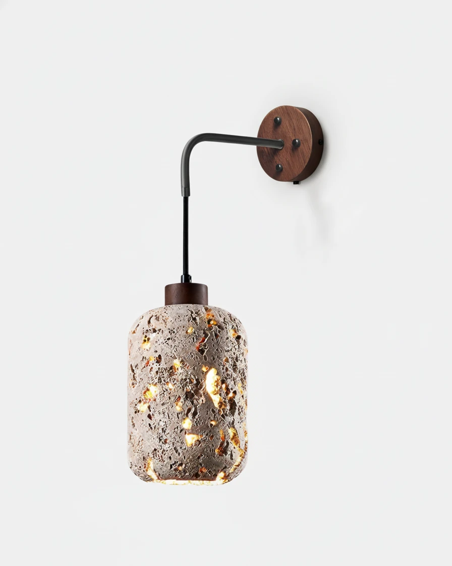 Travertine wall sconce OLTRE No.01, porous stone lantern glowing from a black arm on a round walnut backplate