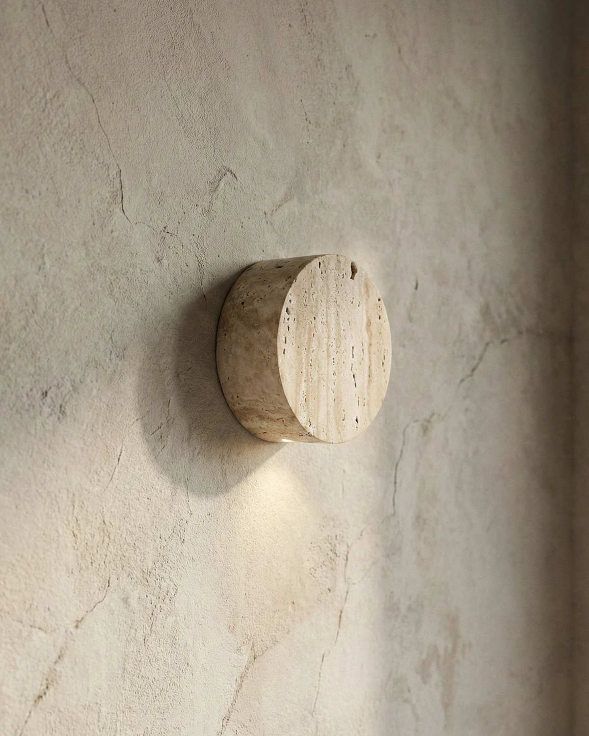 Travertine wall sconce VERONA No.01, veined travertine circle mounted on a textured plaster wall, unlit