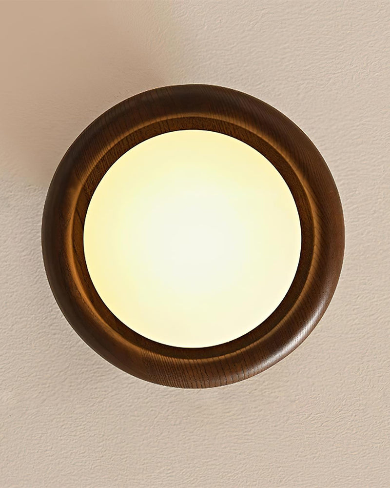 Close-up head-on of the wood flush mount ceiling light MURA No.01 switched on, lit opal disc within a walnut halo