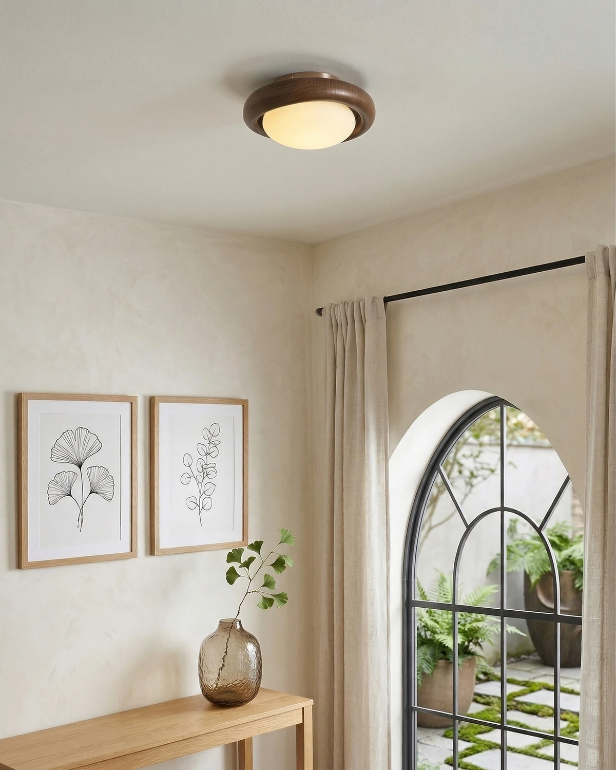 Wood flush mount ceiling light MURA No.01 lit on a plaster ceiling above an oak console beside an arched glass door