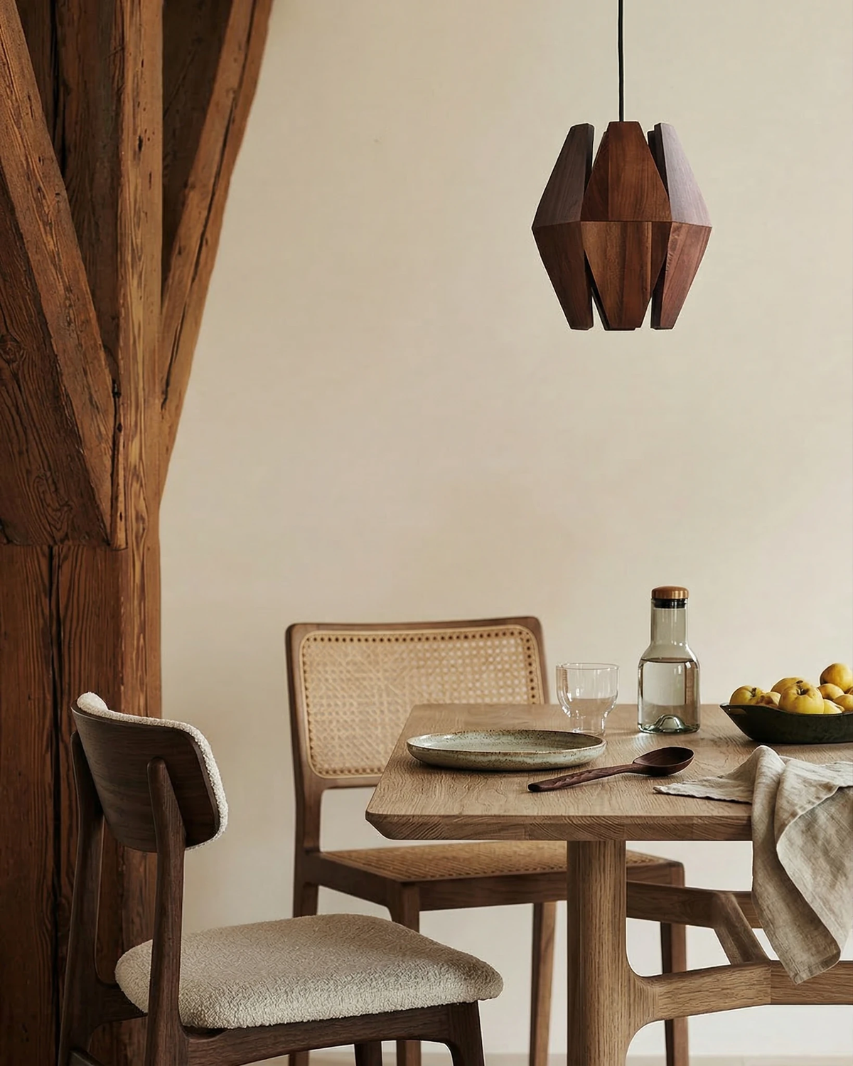 Wood pendant light ORBIT No.01 hanging unlit over an oak dining table with cane chairs beside rustic timber beams