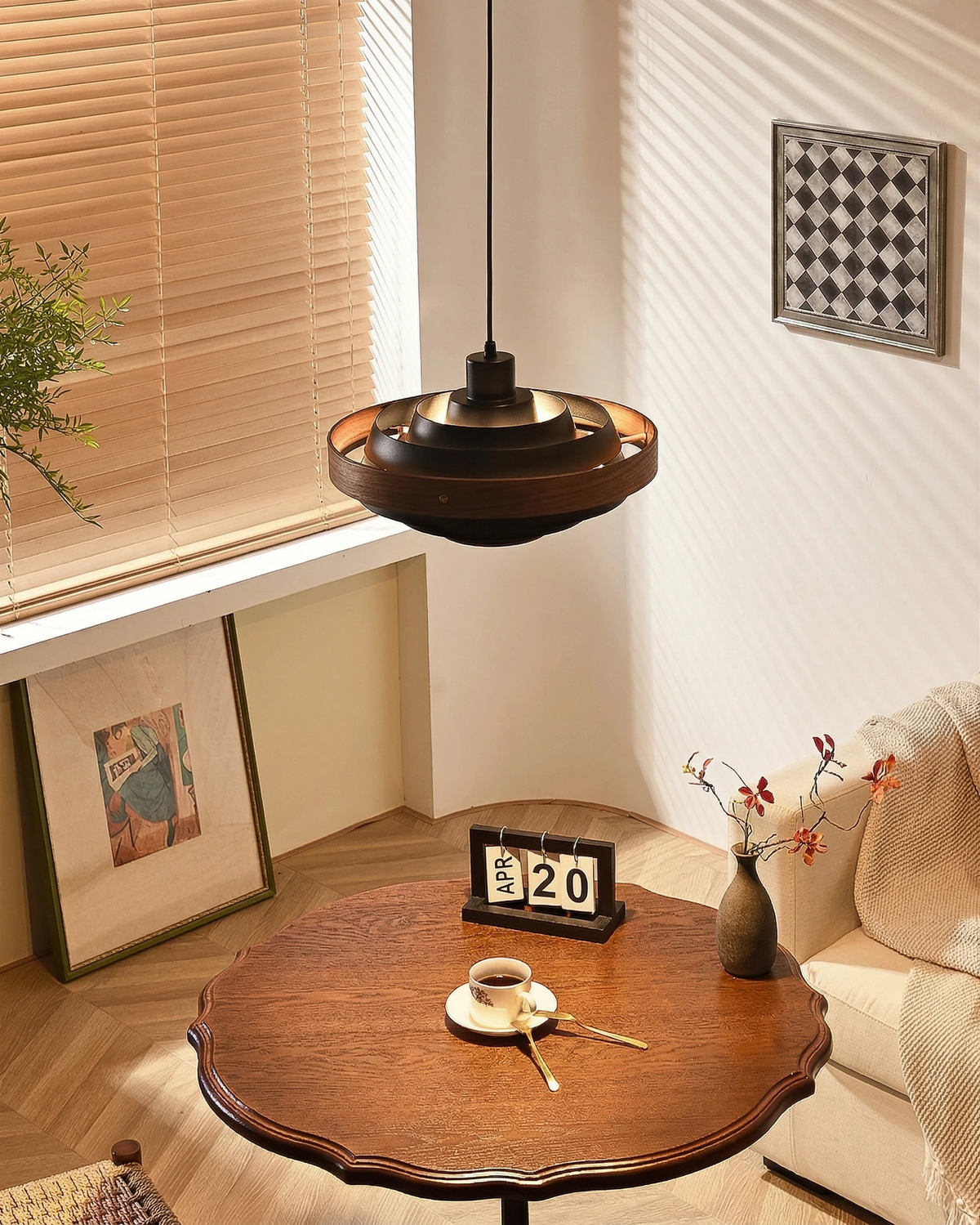Wood pendant light STECCA No.01 in black with walnut ring, lit above a small round wooden table with a coffee cup