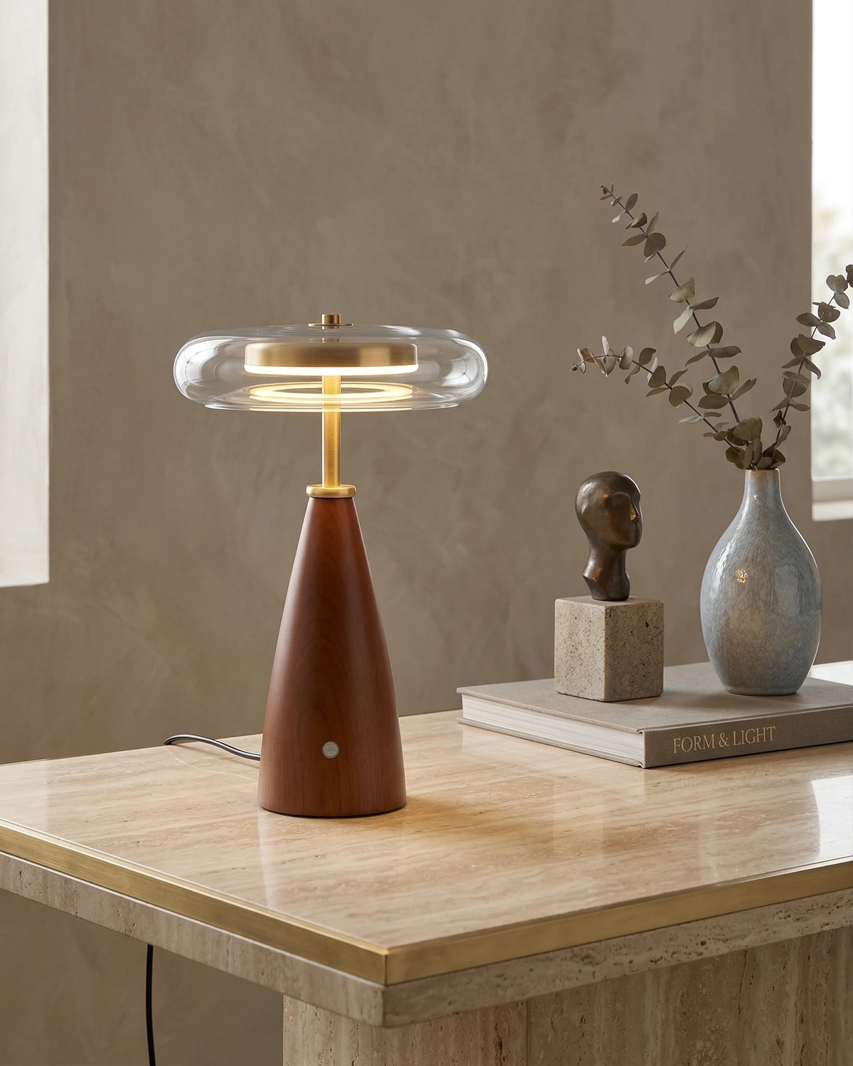 Wood table lamp ROCCA No.01 lit on a travertine console beside a small bust and a vase of dried stems