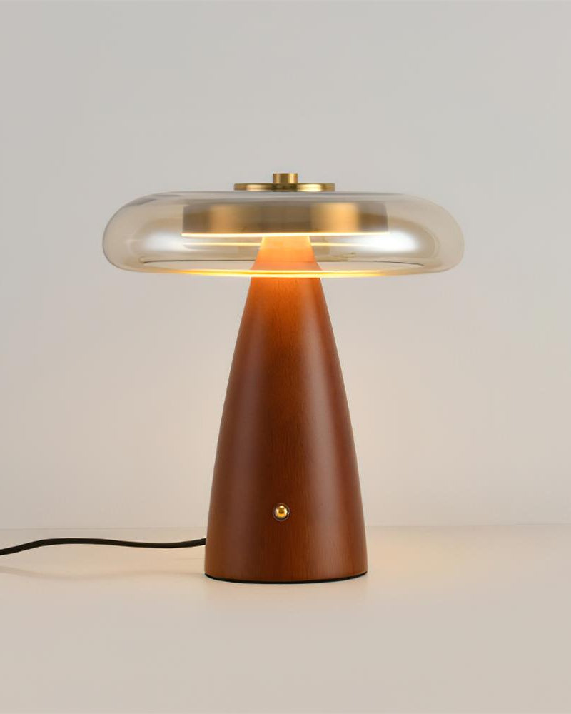 Wood table lamp ROCCA No.01 switched on, ribbed glass shade glowing above the walnut base, cord visible