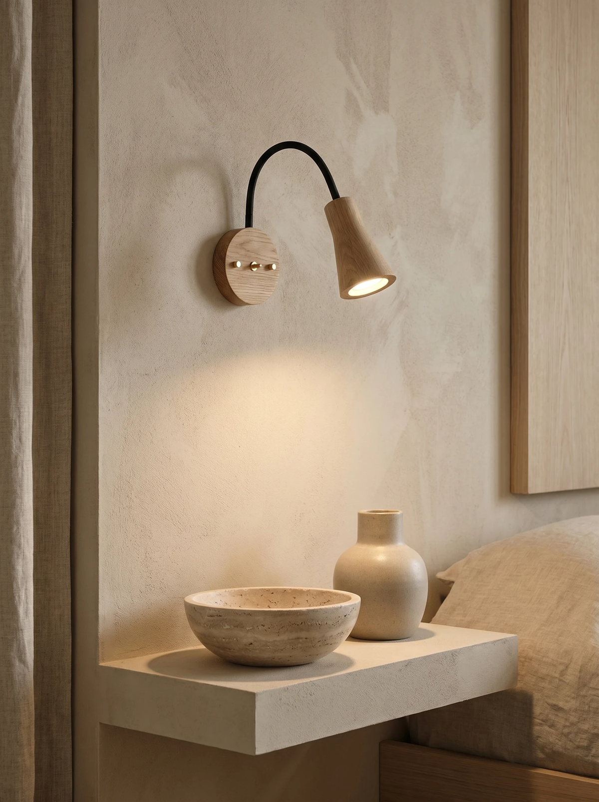 Wood wall sconce RIGA No.07 in light ash switched on above a white ledge with a stone bowl and vase