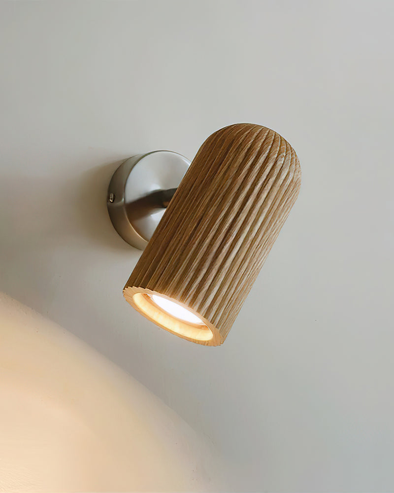 Wood wall sconce NOTA No.01, fluted light wood spot head on a nickel bracket casting a beam down the wall