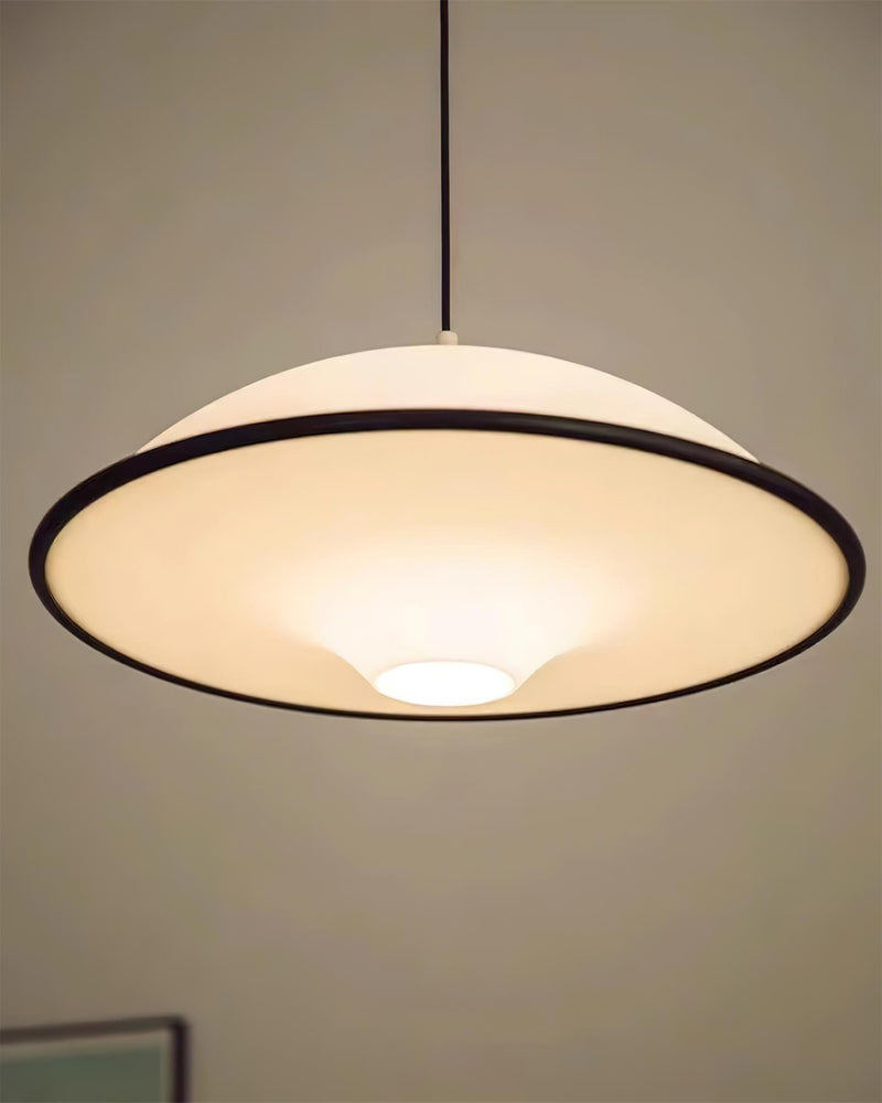 Acrylic pendant light AOSTA No.01 with black rim switched on, saucer glowing near an arched steel window