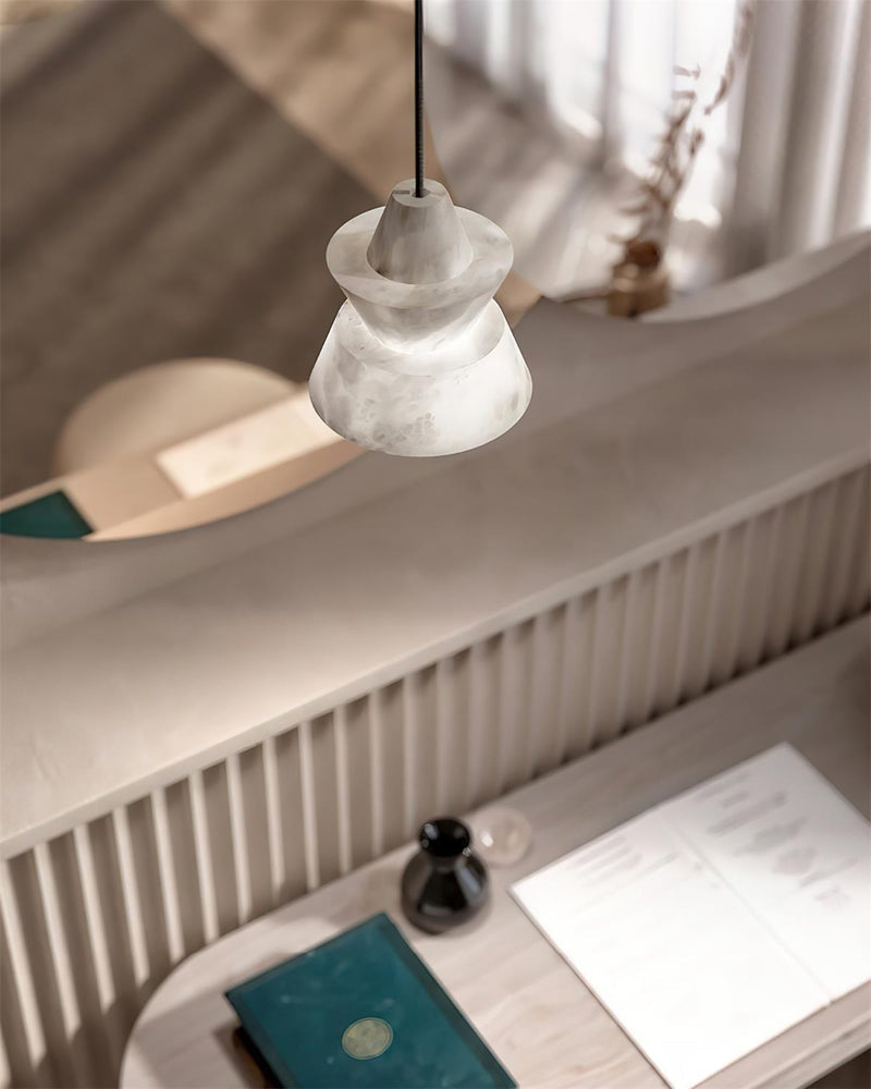 Alabaster pendant light ALABA No.06 hanging lit over a white desk with papers and a notebook near a fluted wall