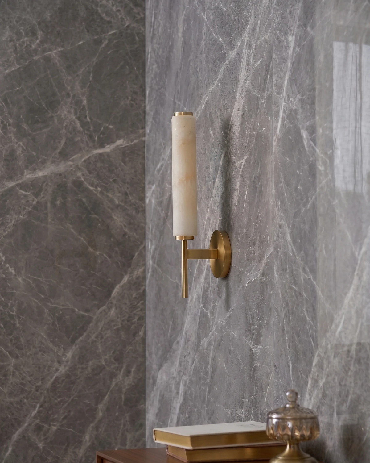 Alabaster wall sconce ALABA No.01 in brushed brass on a gray marble bathroom wall