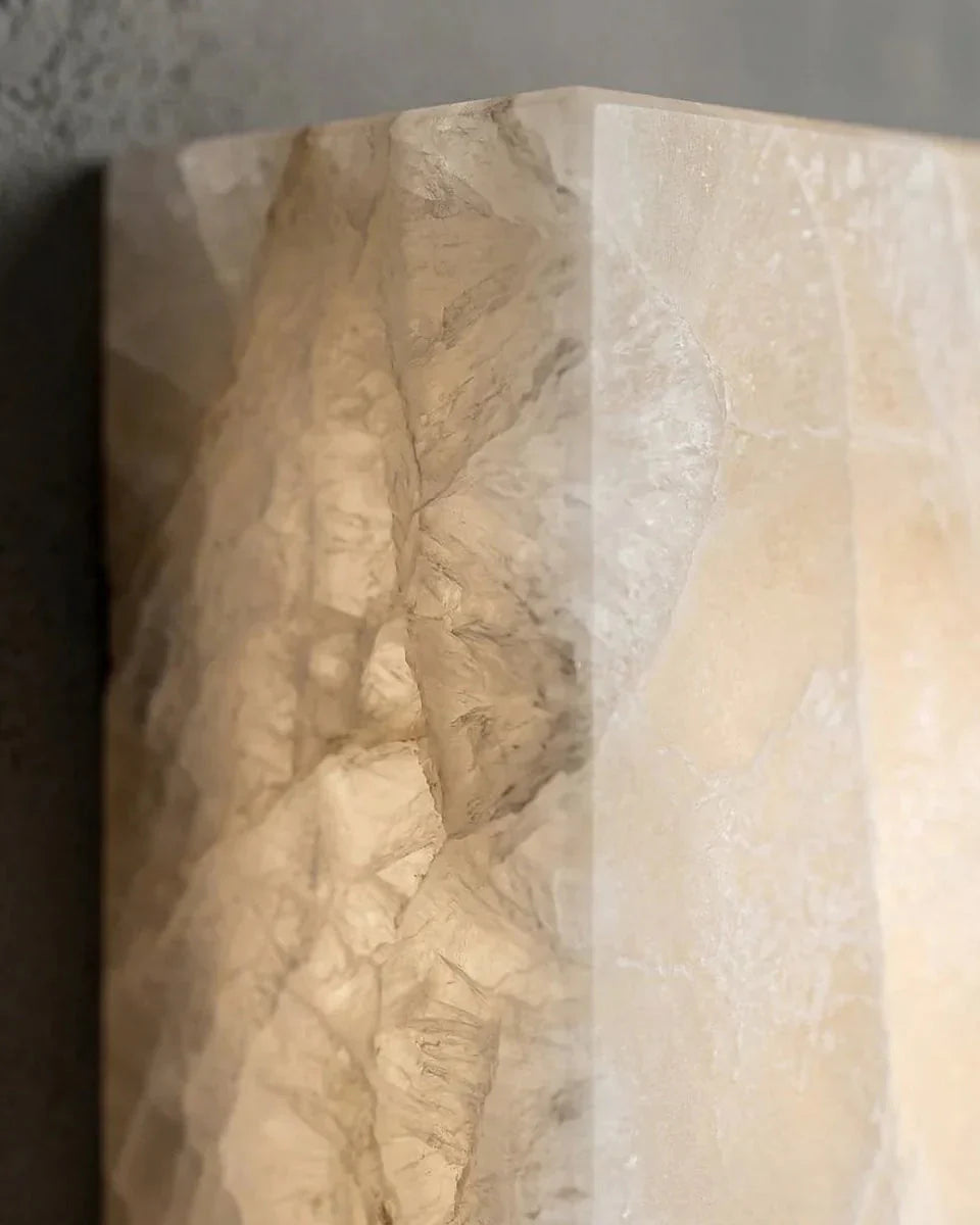 Close-up of the veined white alabaster surface of the ALABA No.03 alabaster wall sconce, lit from within