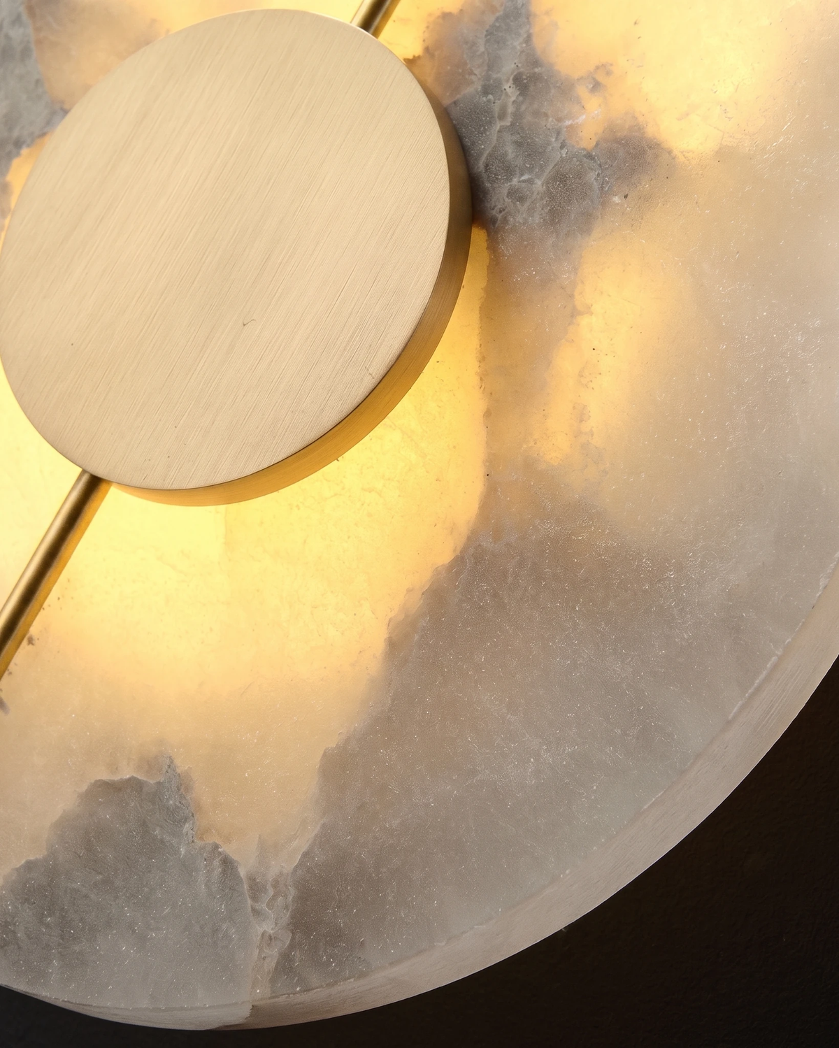Close-up of the lit alabaster veining and brass disc of the OLIVA No.03 wall sconce