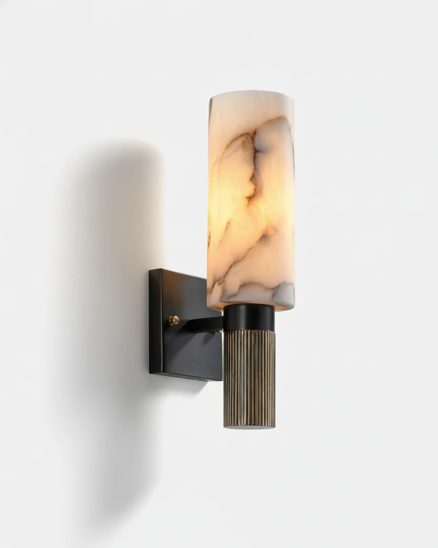 Alabaster wall sconce ALABA No.07, veined cream alabaster cylinder glowing above a fluted brass base on a black bracket