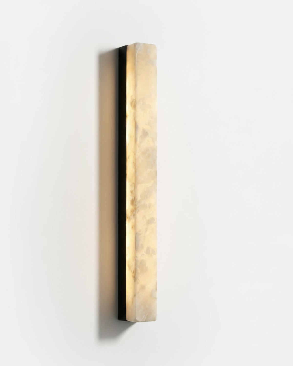 Alabaster wall sconce NEBBIA No.02, 32 in column on a Volcano Black bar, lit, angled view on a white wall