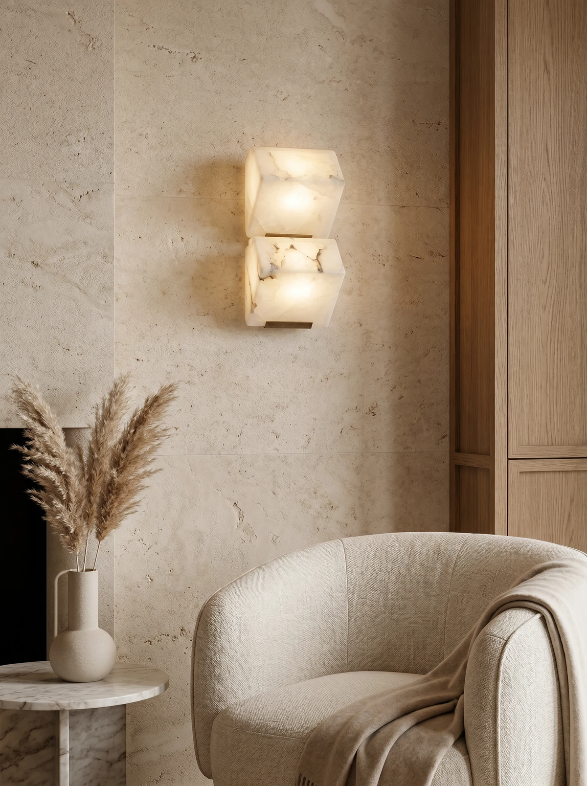 Alabaster wall sconce ALABA No.05 duo lit on a stone wall beside a boucle armchair and pampas grass