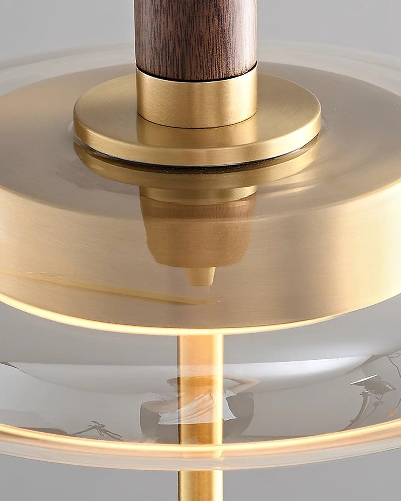 Close-up of the walnut stem and brass collar over the lit glass disc of the NOCE No.01 amber glass pendant light