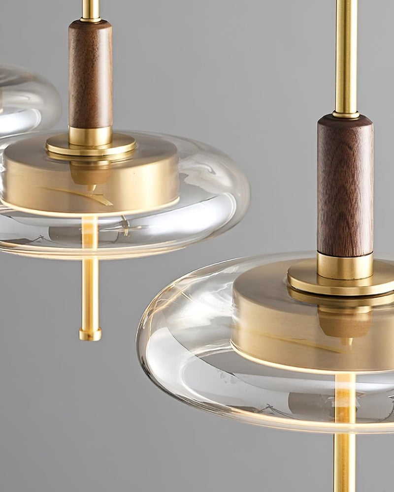 Close-up of two NOCE No.01 amber glass pendant lights showing the walnut stems and brass discs
