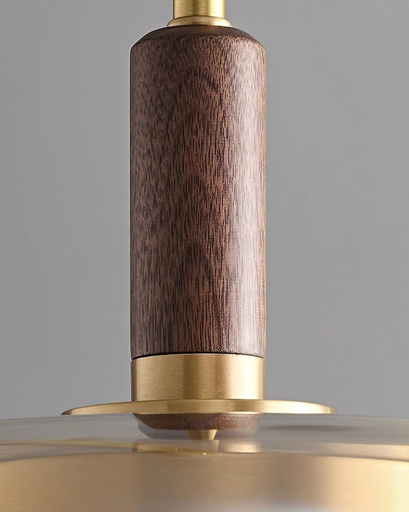 Close-up of the walnut cylinder and brass ring atop the glass disc of the NOCE No.01 amber glass pendant light
