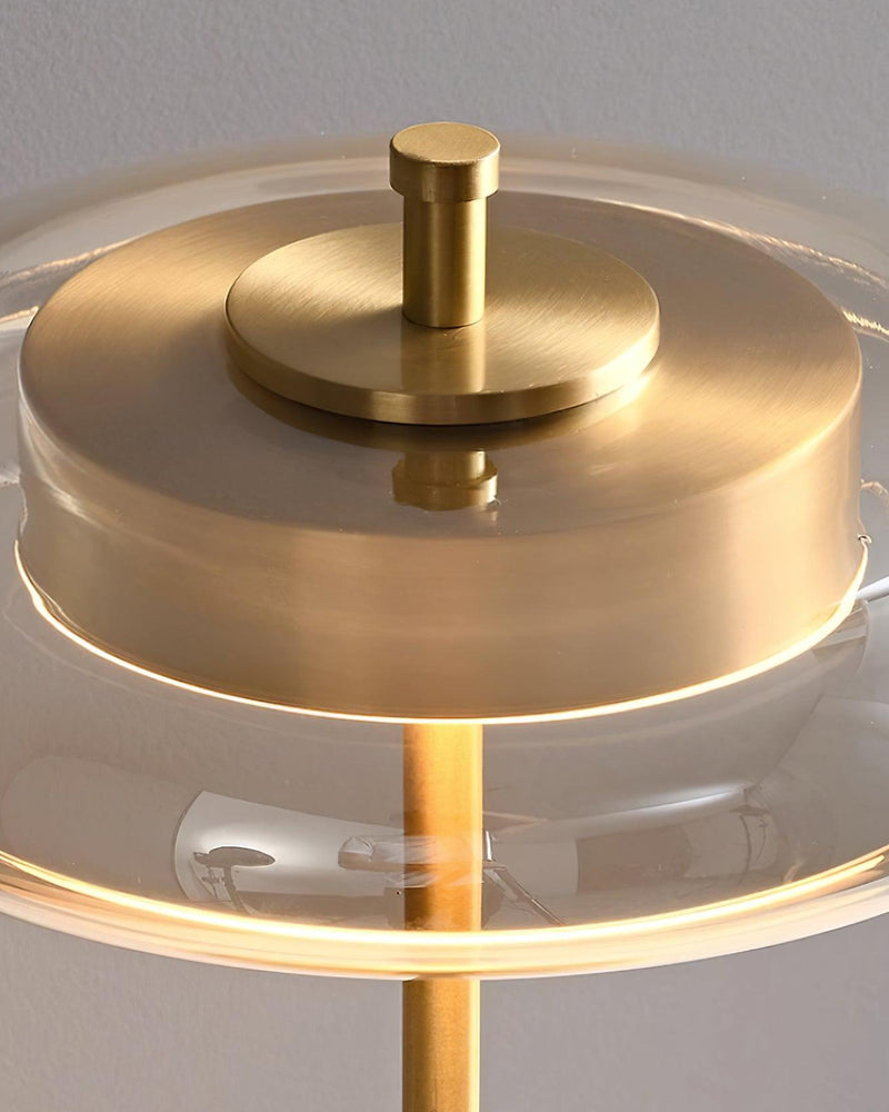 Close-up of the amber glass table lamp TARO No.02 shade switched on, brass disc glowing inside the tinted glass