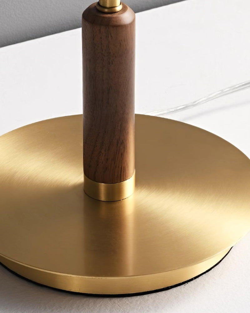 Close-up of the round brass base of the amber glass table lamp TARO No.02 with the walnut column above it