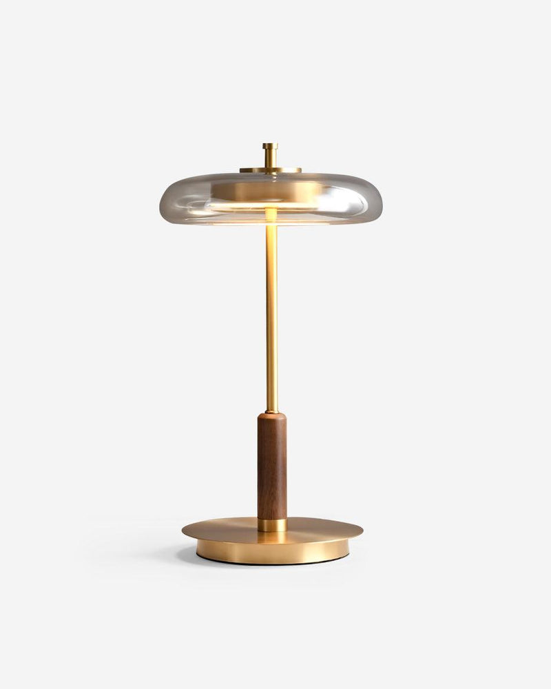 Amber glass table lamp TARO No.02 with a tinted glass disc shade lit, brass stem, walnut grip and round brass base