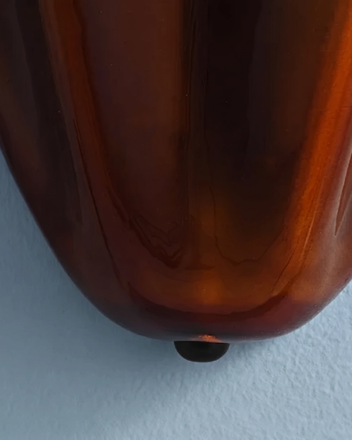Close-up of the amber brown glass base and brass finial of the brass wall sconce DALIA No.03