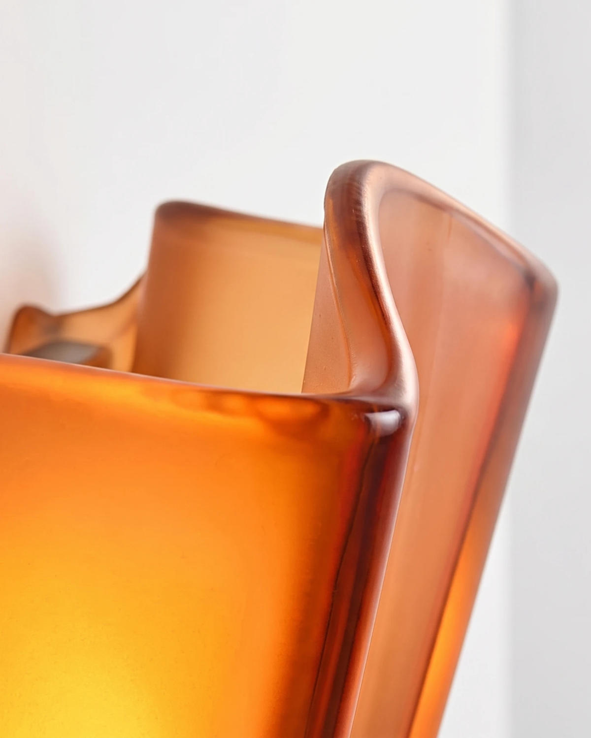 Close-up of the amber brown glass corolla of the brass wall sconce DALIA No.03 glowing when switched on