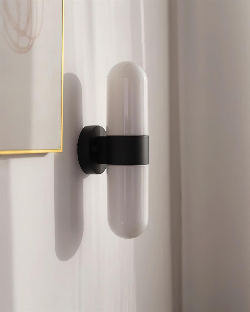 Close-up of the matte black band and bracket of the COMETA No.01 brass wall sconce with opal capsules, unlit
