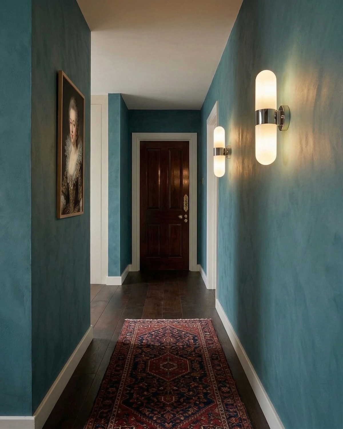 Brass wall sconce COMETA No.01 in polished chrome, two lit units along a teal hallway with a runner rug