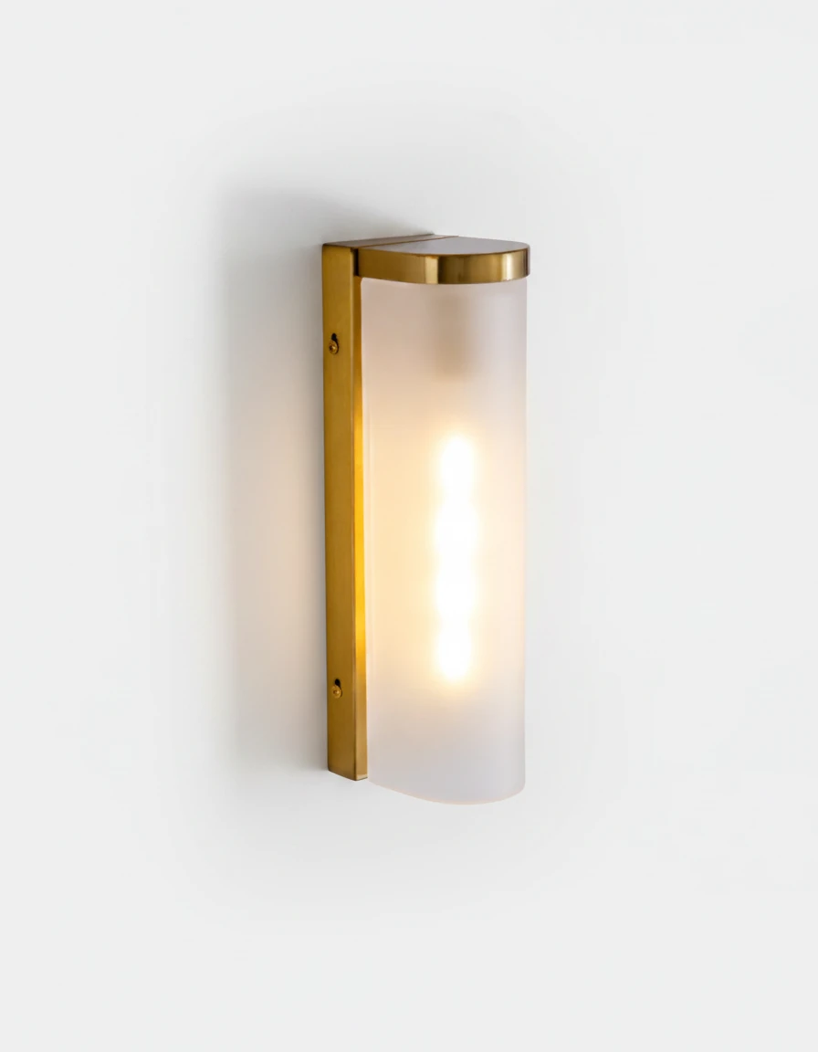 Brass wall sconce PILA No.01 Single Column, frosted glass shield on an antique brass bracket, lit