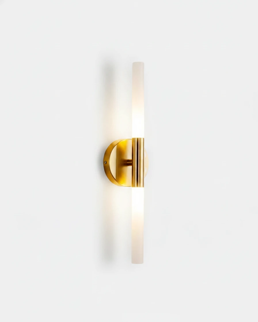 Brass wall sconce STELO No.01 in antique gold, slim vertical frosted tube on a half-round bracket, switched on