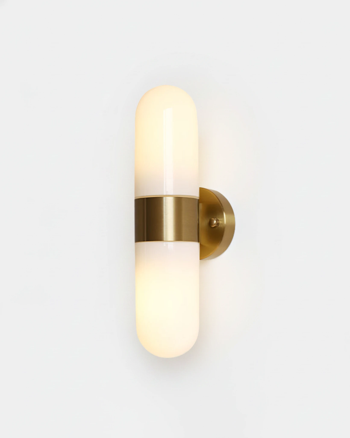 Brass wall sconce COMETA No.01 in Brushed Brass, vertical twin opal capsules with a brass center band, lit