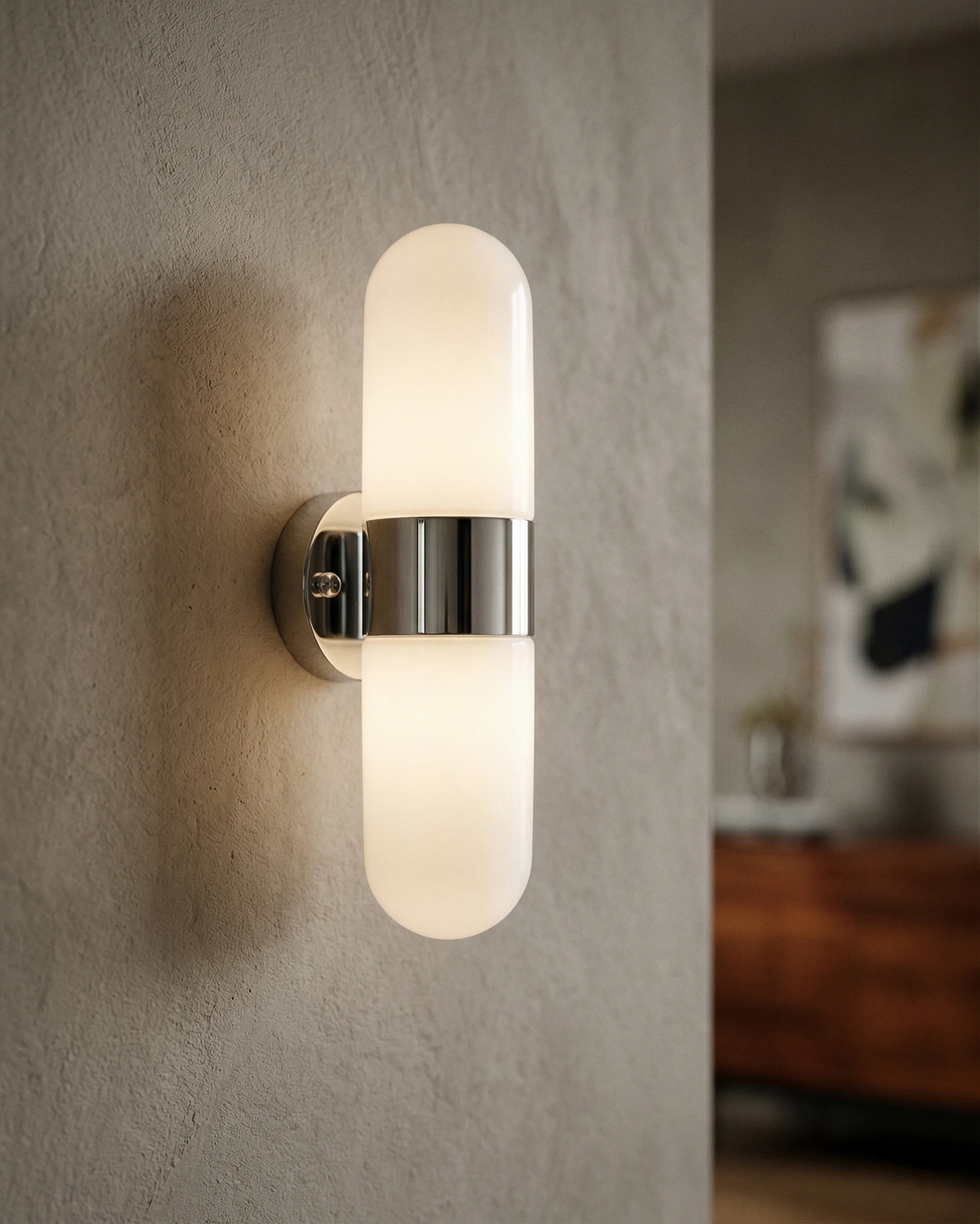 Brass wall sconce COMETA No.01 in polished chrome switched on against a textured plaster wall