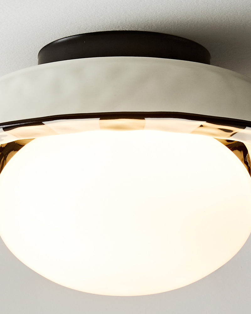 Close-up of the lit opal globe and polished petal ring of the OLEA No.02 ceramic flush mount ceiling light