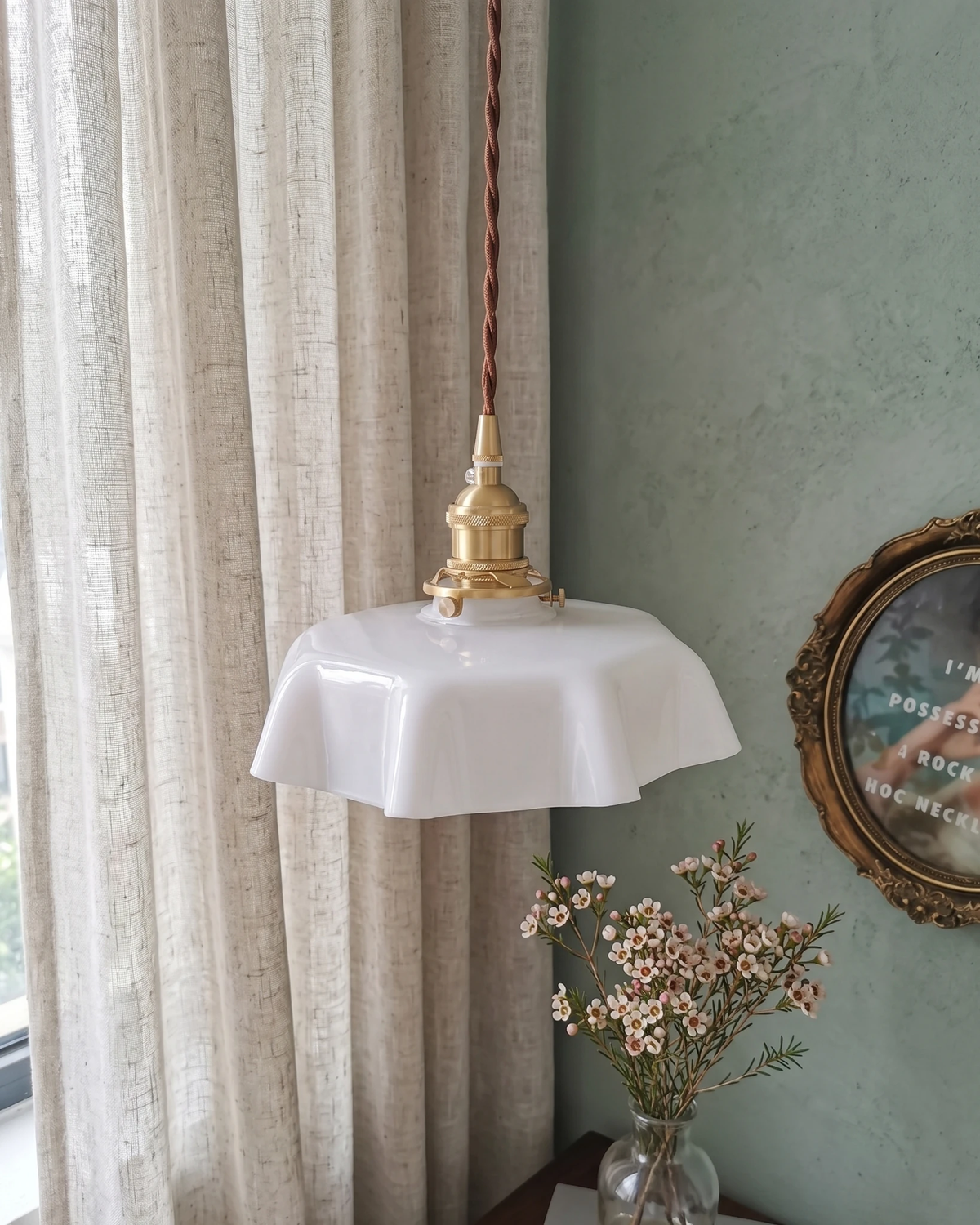 Ceramic pendant light CORA No.01 in bone white lit by a curtained window with a vase of flowers and teal wall