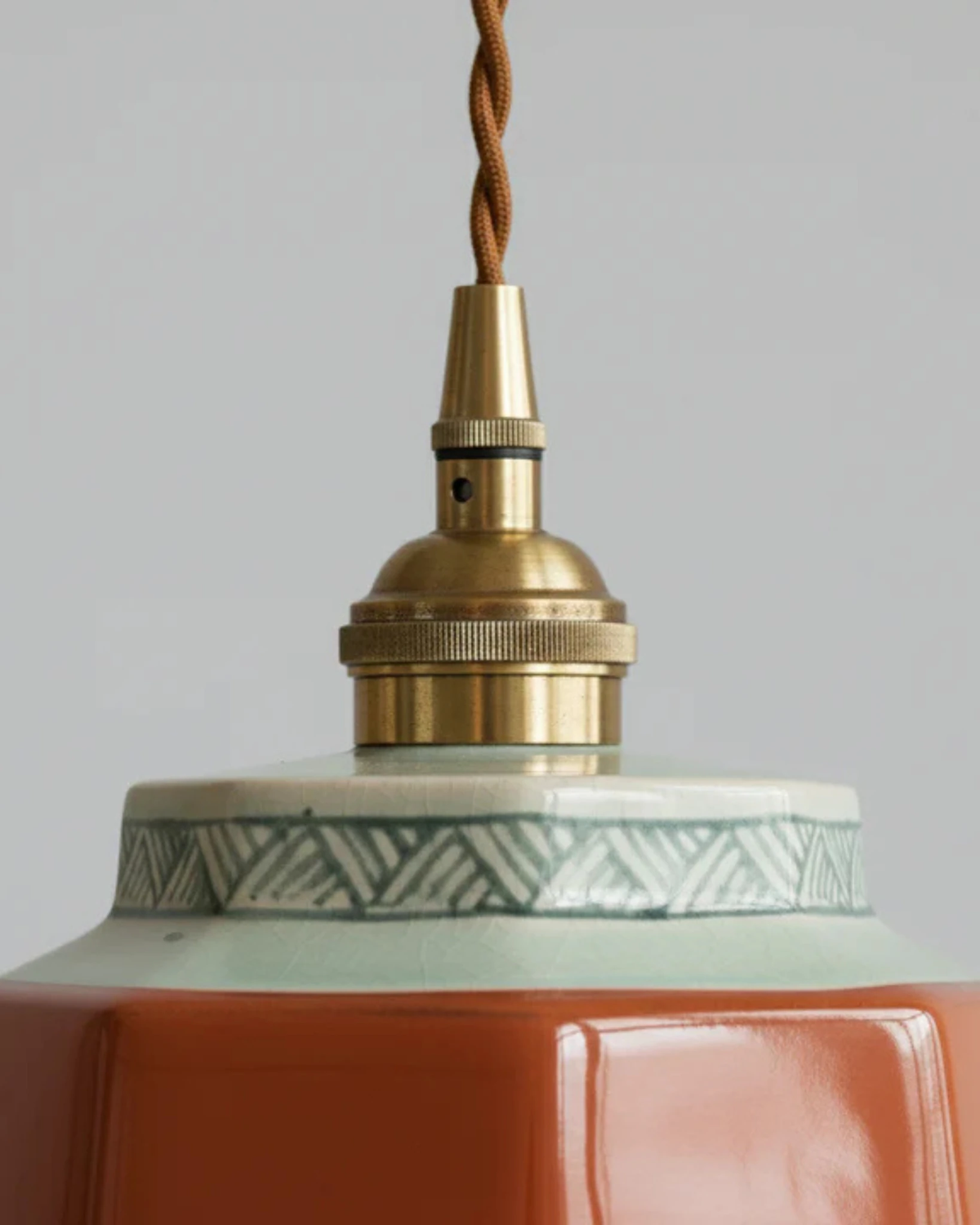 Close-up of the RAGUSA No.01 ceramic pendant light in oxblood red, brass socket and patterned ceramic band