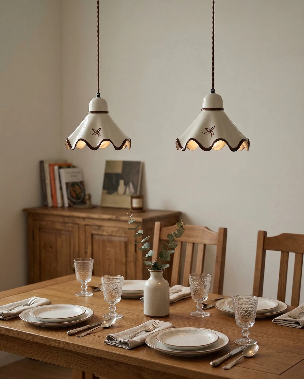 Two ceramic pendant lights CAPRI No.01 switched on above a set oak dining table with wooden chairs and a sideboard