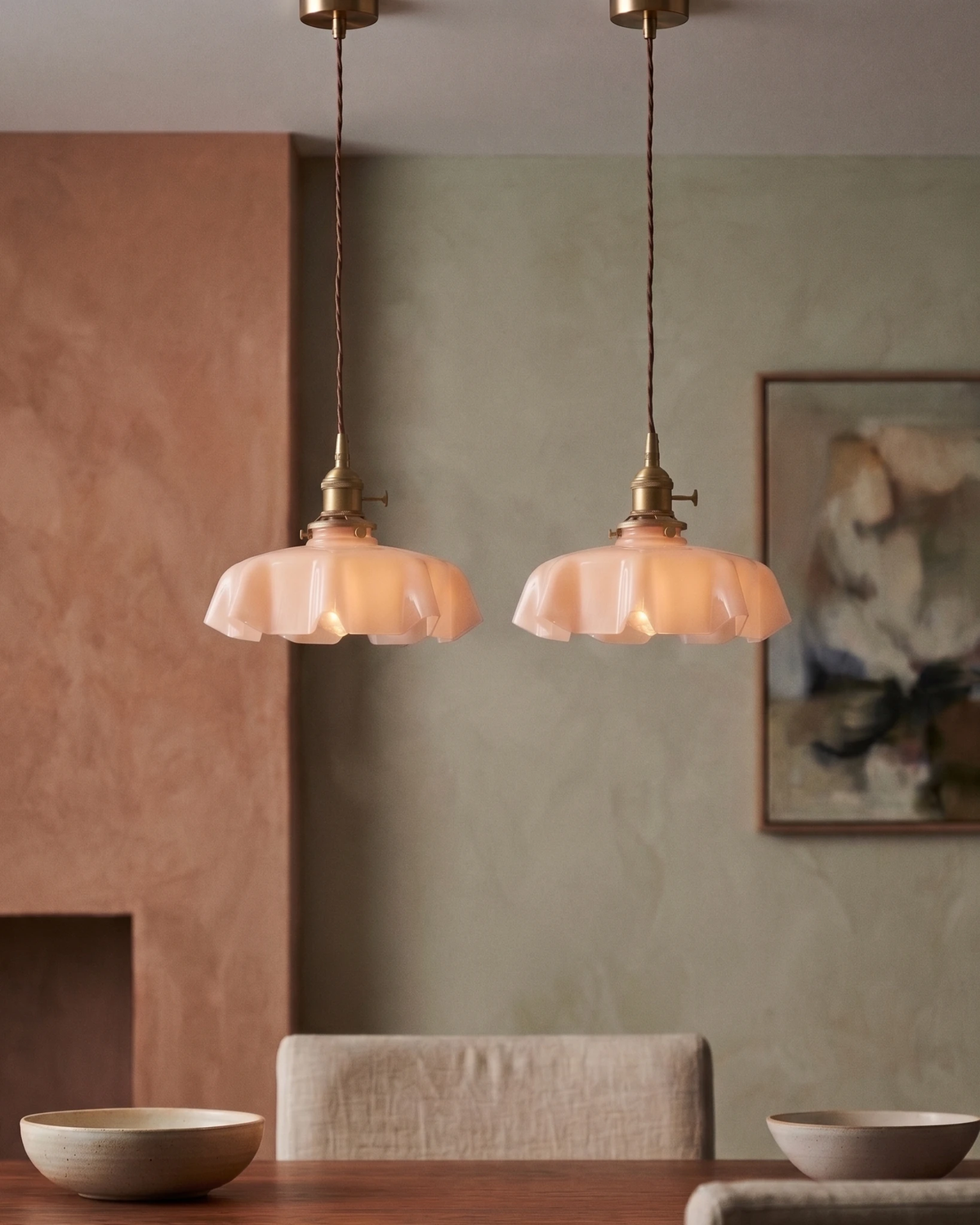 Two ceramic pendant lights CORA No.01 in dusty rose lit above a dining table with bowls in a plaster-walled room