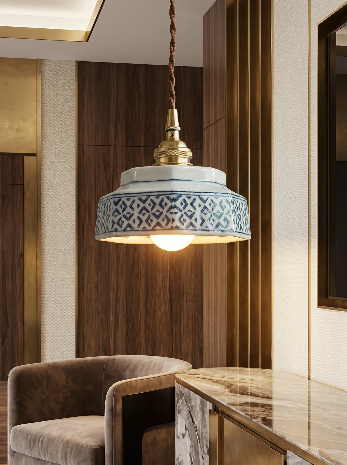 Ceramic pendant light RAGUSA No.02 with a geometric painted shade lit over a marble counter beside a velvet chair