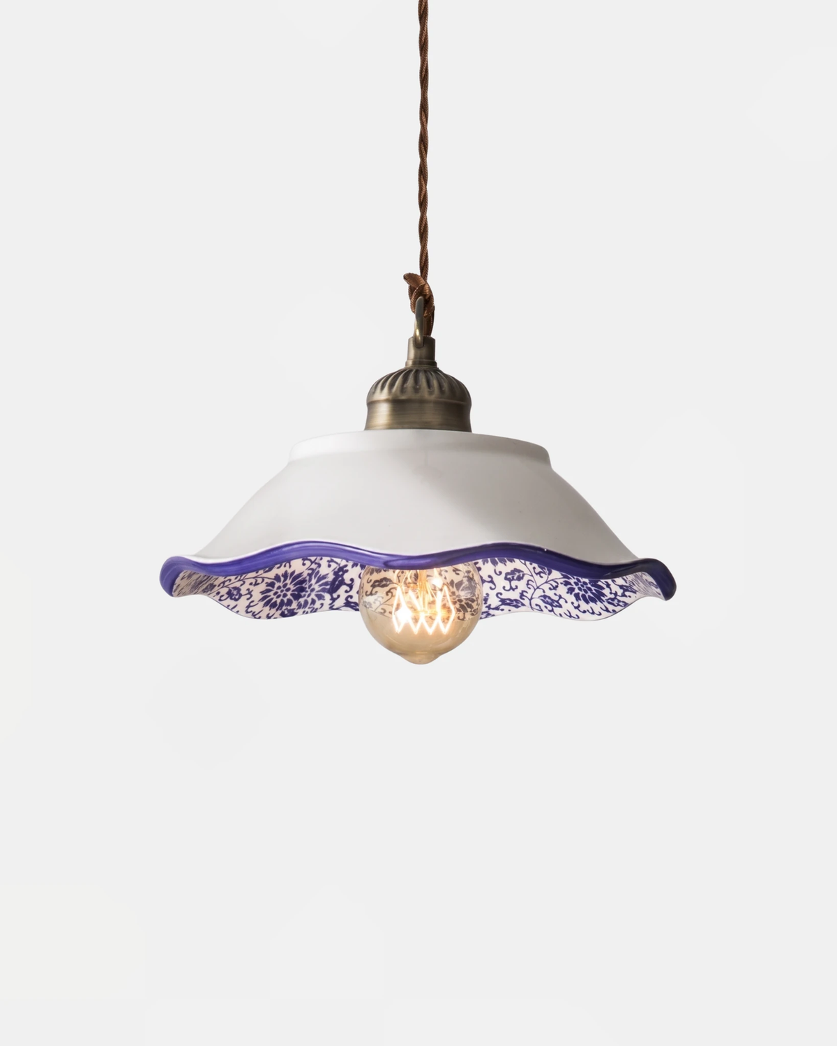 Ceramic pendant light MELI No.01 in the Corolle stepped bell shape, wavy blue floral rim with a lit filament bulb