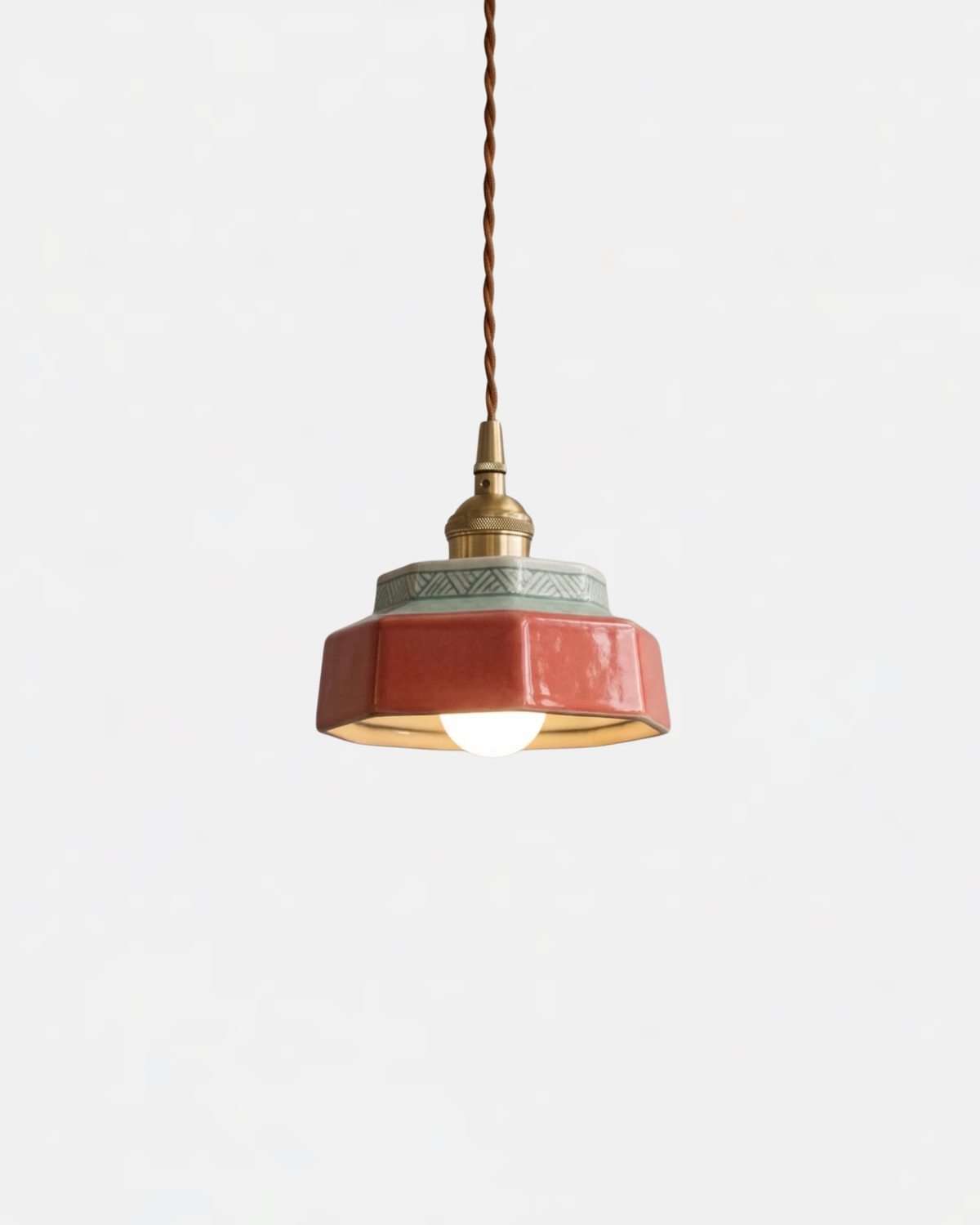 Ceramic pendant light RAGUSA No.01 in Oxblood Red with brass collar on a twisted cord, bulb switched on