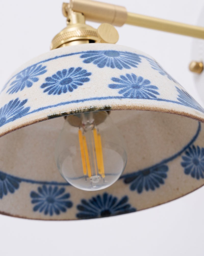Close-up of the FIORA No.01 ceramic sconce shade with brass arm and filament bulb