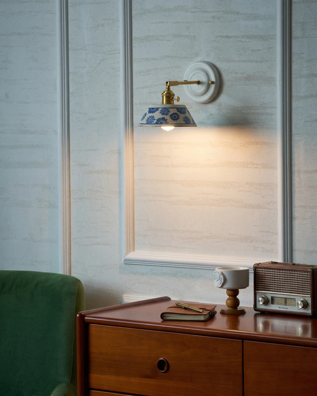 Ceramic wall sconce FIORA No.01 lit above a wooden dresser
