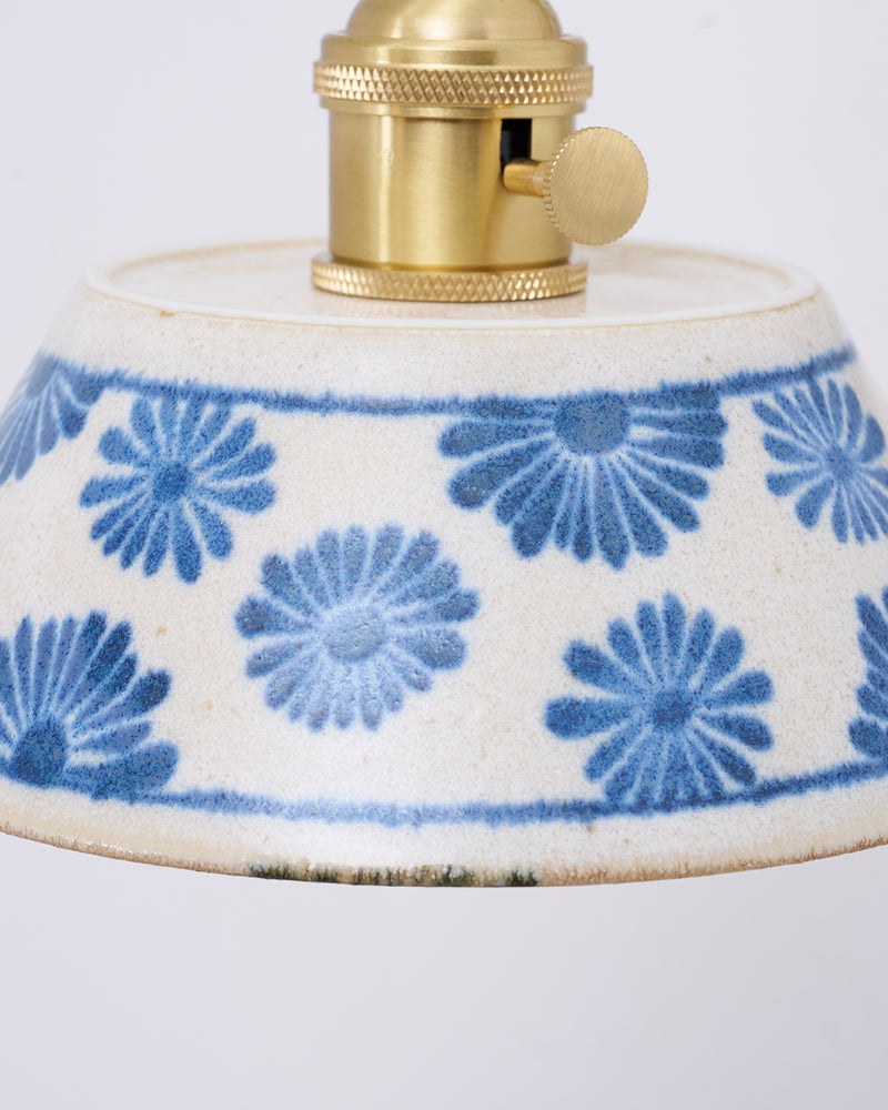 Close-up of the hand-painted blue flowers on the FIORA No.01 ceramic shade with brass socket