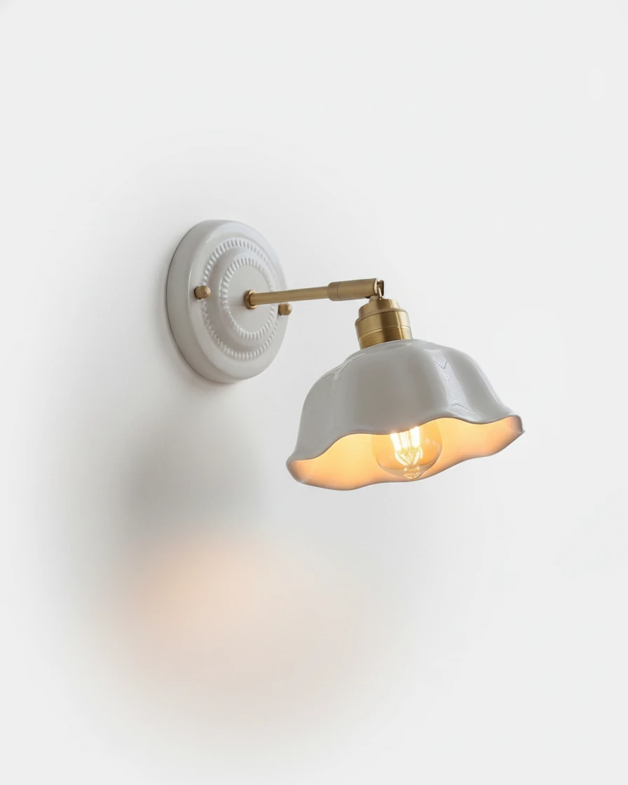 Ceramic wall sconce RIGA No.05, white scalloped petal shade on an antique brass swing arm, bulb lit
