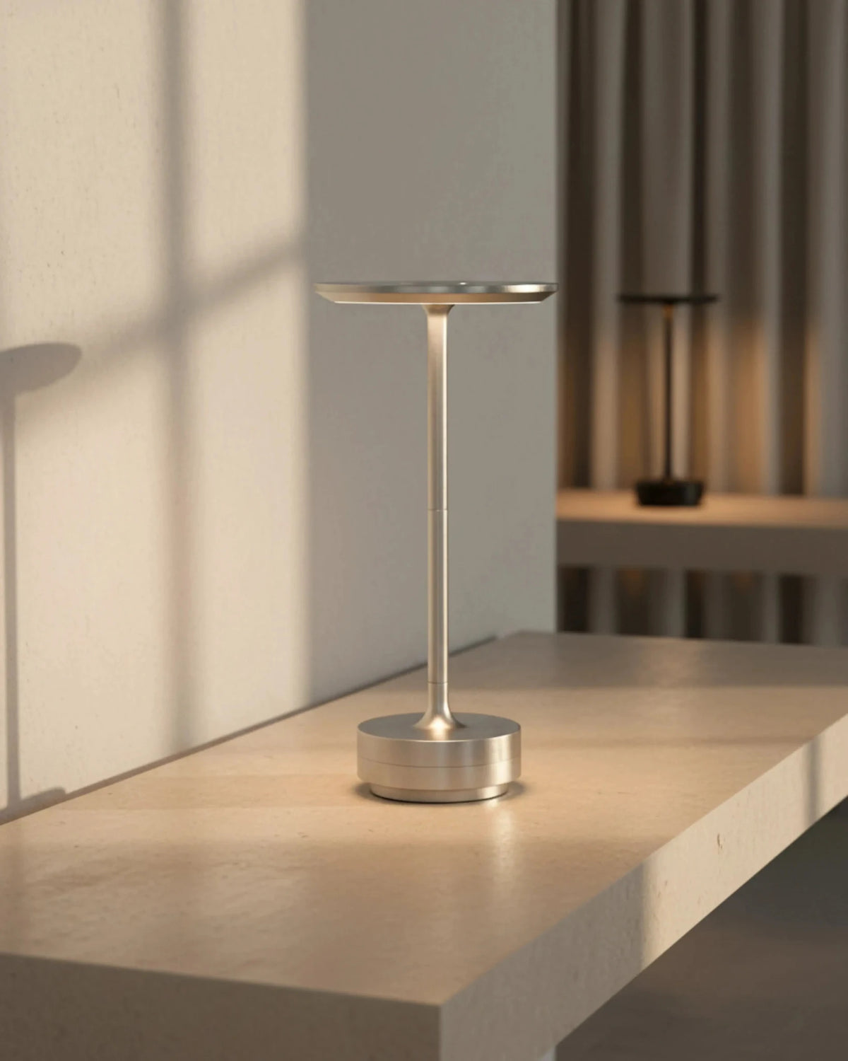 Cordless desk lamp LUMA No.05 in silver lit on a wooden desk in a neutral office with curtains