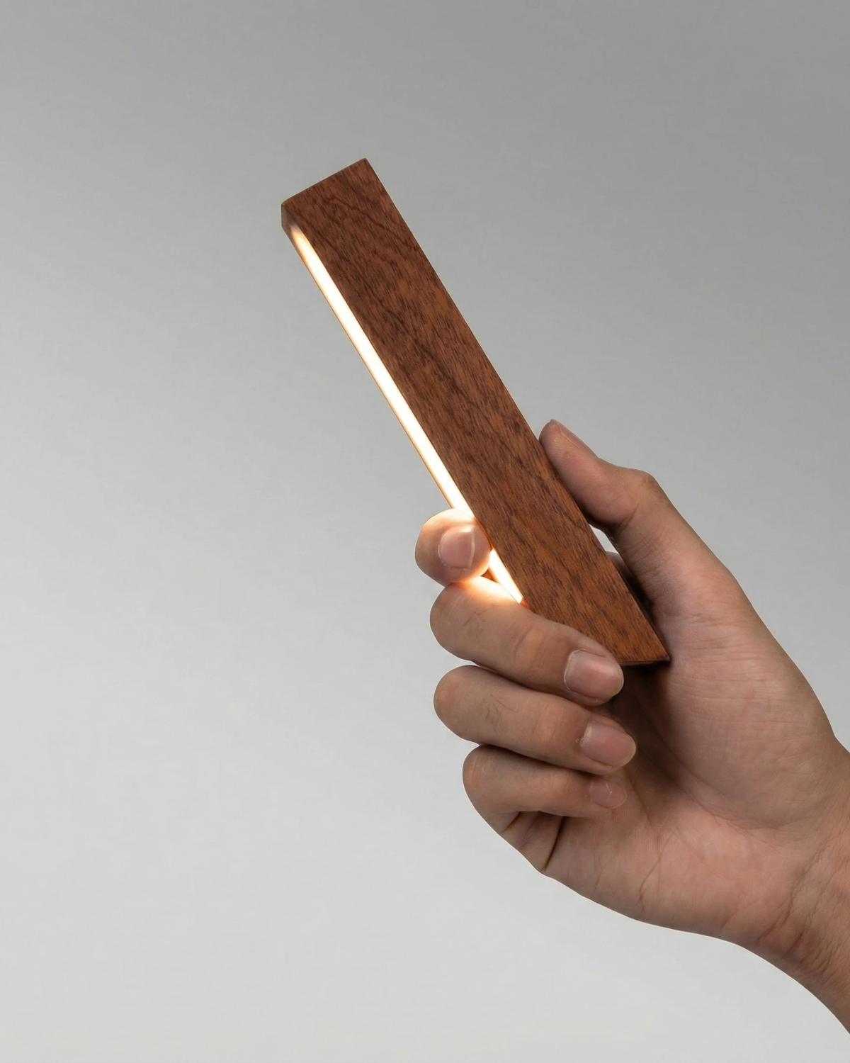 Close-up of a hand holding the detached lit head of the RAMO No.01 cordless desk lamp