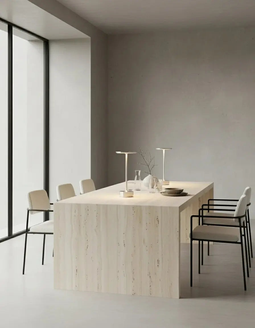 Two cordless desk lamps LUMA No.05 in silver standing on a travertine dining table with chairs