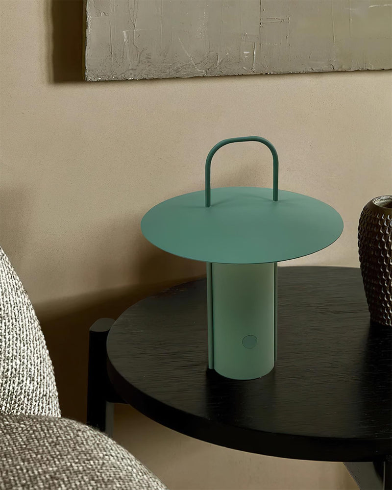 Cordless lantern lamp PORTO No.01 in forest green lit on a black side table beside a sofa