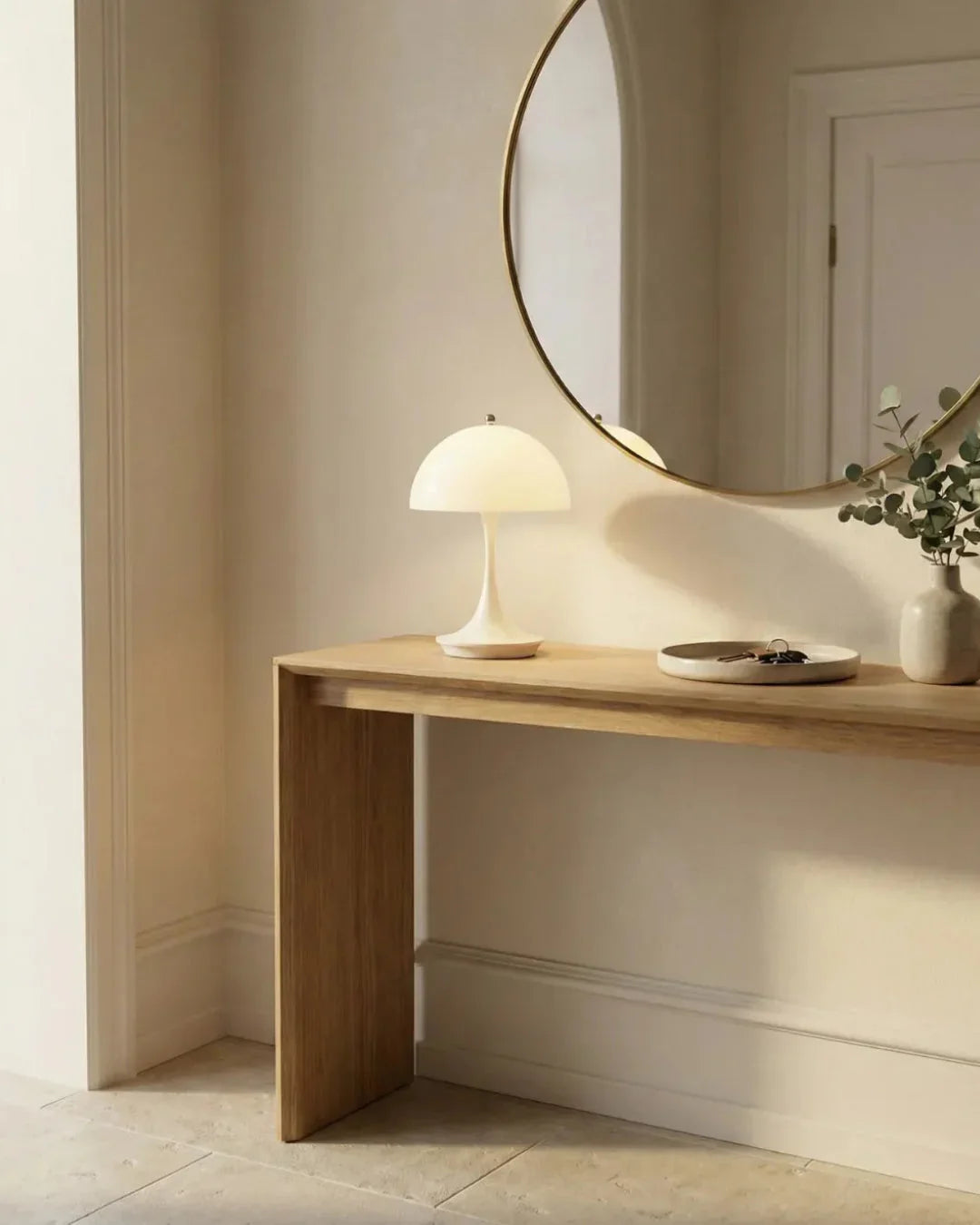 Cordless mushroom lamp FONTE No.01 in soft white lit on a wooden console beneath a round mirror