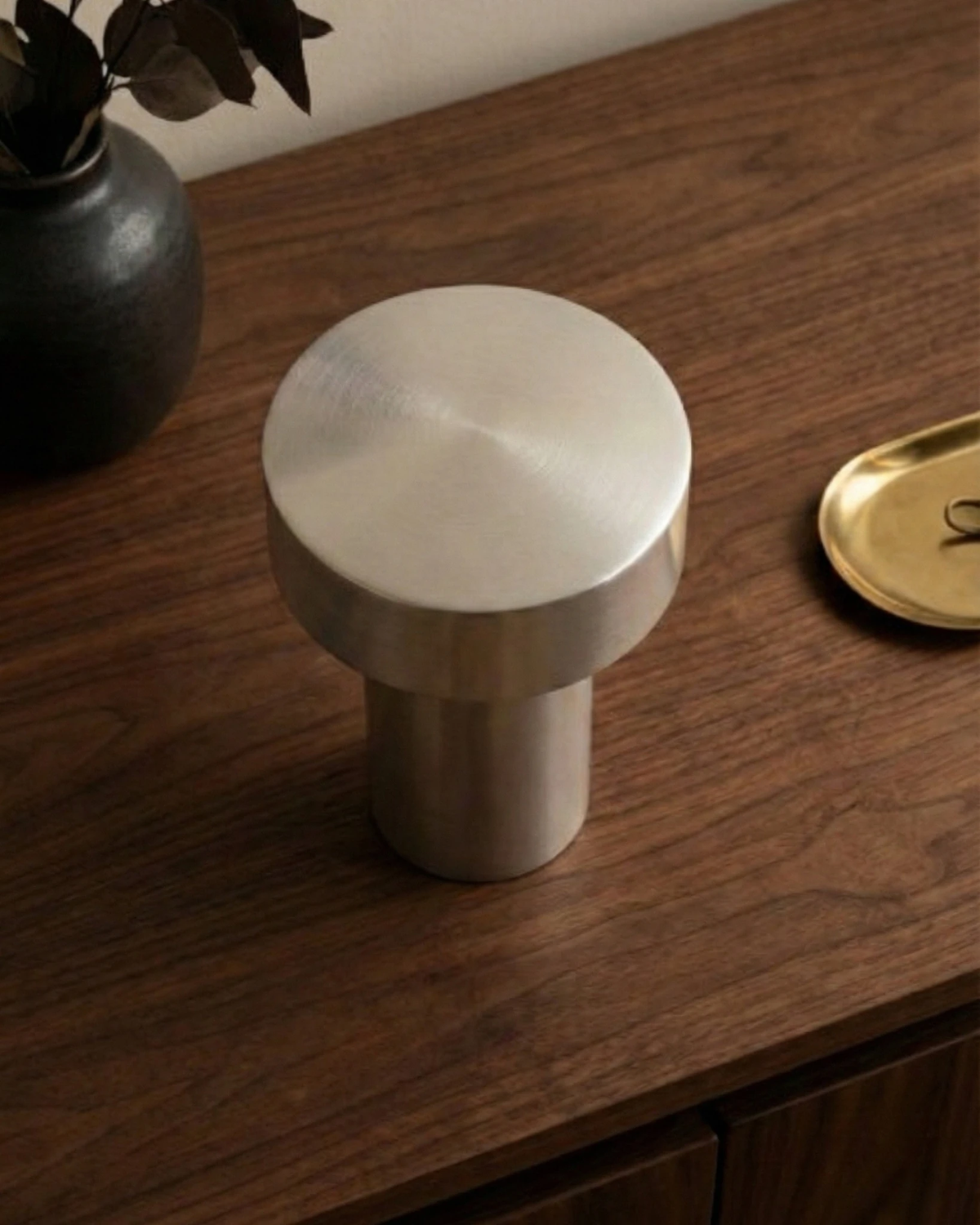 Close-up of the brushed aluminum cap of the PADOVA No.01 cordless mushroom lamp standing on a walnut surface